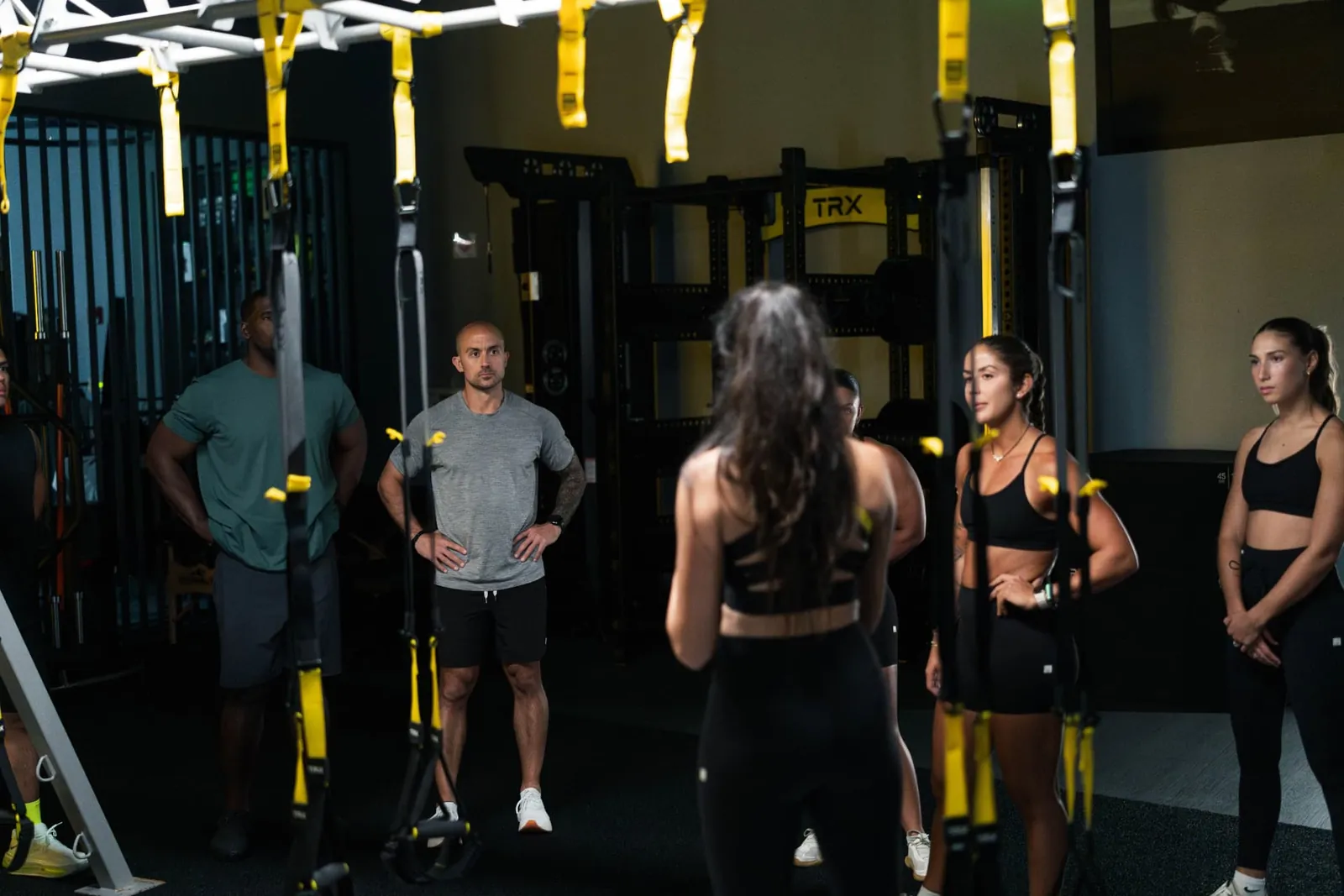 A coach briefing a small group of members under TRX straps at Check Fitness