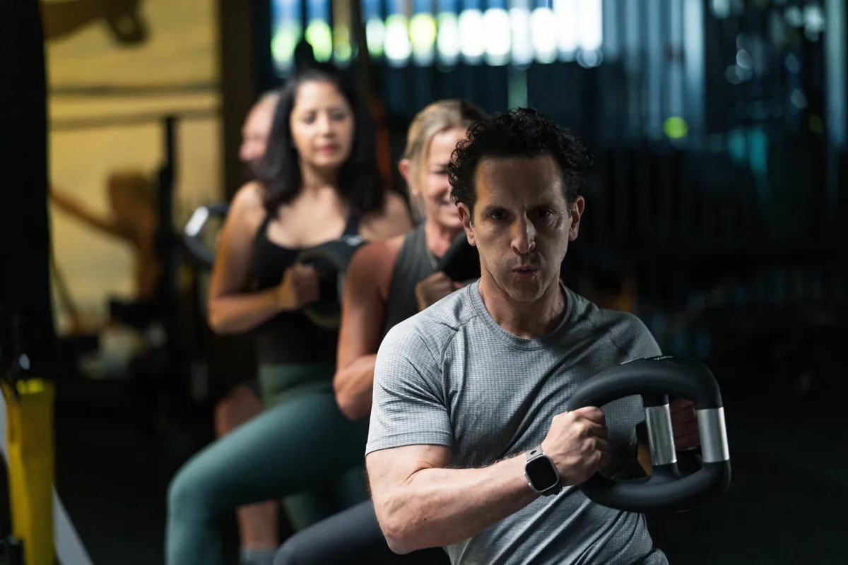 Members swinging kettlebells in a line during a coached class at Check Fitness